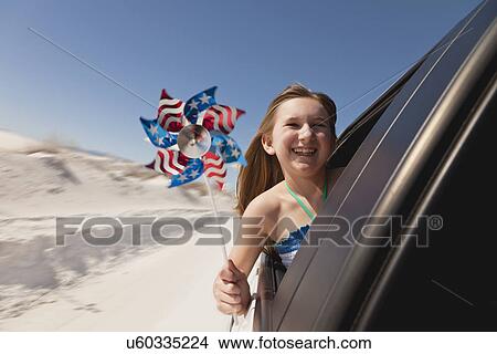 Picture - USA, New Mexico, Whitesands, Girl (10-11) looking through car's window and holding pinwheel. Fotosearch