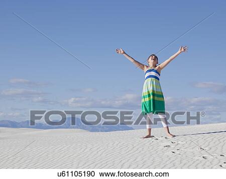 Stock Image - USA, New Mexico, Whitesands, Girl (10-11) with outstretched hands at desert. Fotosearch