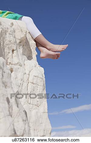 Stock Photograph - USA, New Mexico, Whitesands, Girl (10-11) sitting at the edge of rock, low section. Fotosearch