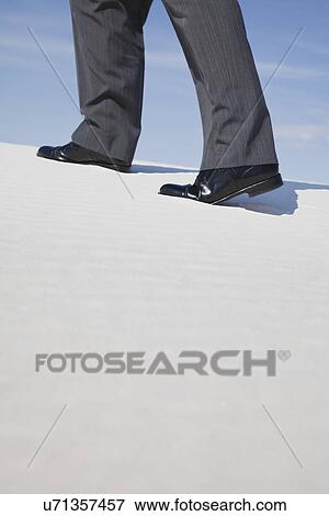 Stock Photo - USA, New Mexico, Whitesands, Low section of man wearing suit walking on desert. Fotosearch