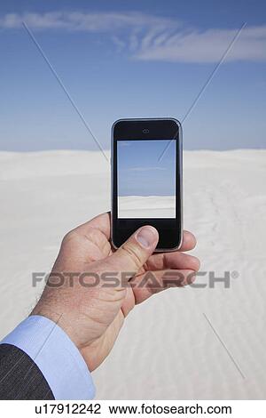 Stock Image - USA, New Mexico, Whitesands, Man taking photo on desert. Fotosearch