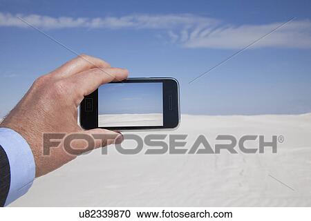 Stock Image - USA, New Mexico, Whitesands, Man taking photo on desert. Fotosearch