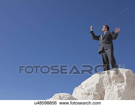 Stock Photograph - USA, New Mexico, Whitesands, Mid adult businessman gesturing with mobile phone. Fotosearch