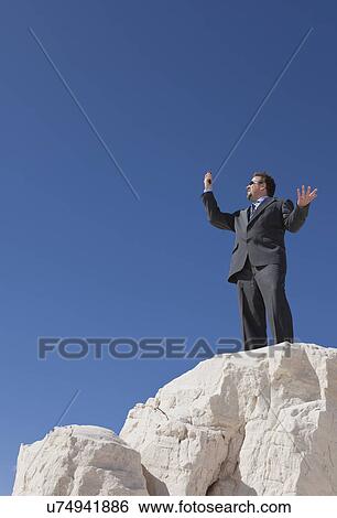 Stock Photograph - USA, New Mexico, Whitesands, Mid adult businessman gesturing with mobile phone. Fotosearch