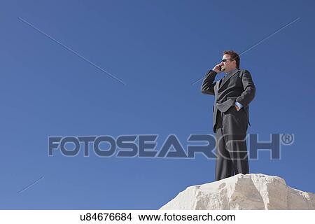 USA, New Mexico, Whitesands, Businessman at the edge of rock talking via phone View Large Photo Image Picture - USA, New Mexico, Whitesands, Businessman at the edge of rock talking via phone. Fotosearch
