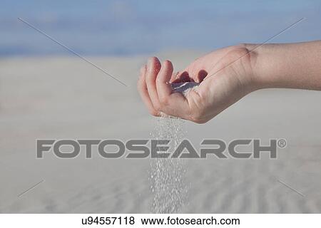 Stock Photo - USA, New Mexico, Whitesands, Sand slipping through fingers. Fotosearch