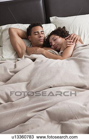 Stock Image - USA, New York City, couple asleep in bed. Fotosearch