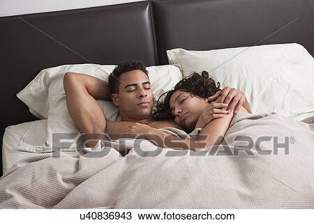 Stock Image - USA, New York City, couple asleep in bed. Fotosearch