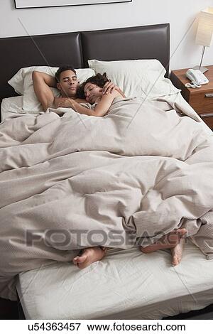 Stock Photo - USA, New York City, couple asleep in bed. Fotosearch