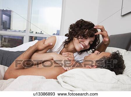 Stock Image - USA, New York City, couple embracing on bed. Fotosearch