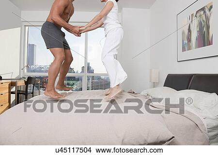 USA, New York City, low section of couple jumping on bed View Large Photo Image Picture - USA, New York City, low section of couple jumping on bed. Fotosearch