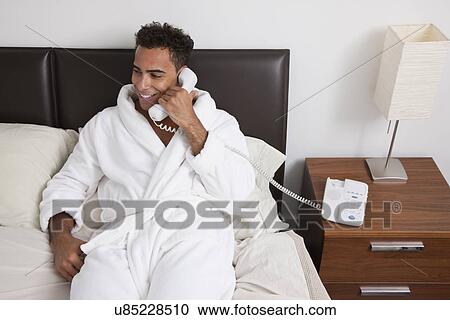USA, New York City, man sitting on bed and talking on phone View Large Photo Image Stock Image - USA, New York City, man sitting on bed and talking on phone. Fotosearch
