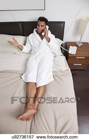 USA, New York City, man sitting on bed and talking on phone View Large Photo Image Stock Photo - USA, New York City, man sitting on bed and talking on phone. Fotosearch