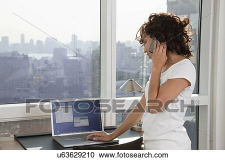 USA, New York City, woman talking on phone and using laptop View Large Photo Image Stock Image - USA, New York City, woman talking on phone and using laptop. Fotosearch