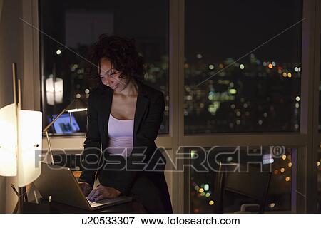 Stock Photo - USA, New York City, woman using laptop in bedroom. Fotosearch