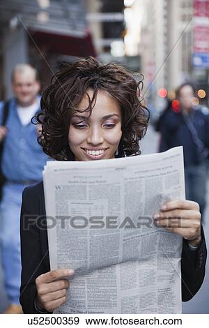 USA, New York, New York City, smiling businesswoman reading newspaper on street View Large Photo Image Stock Photo - USA, New York, New York City, smiling businesswoman reading newspaper on street. Fotosearch