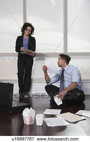 Stock Photo - USA, New York, New York City, businesspeople having meeting in hotel room, discussing documents and eating Chinese take out food. Fotosearch
