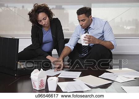 USA, New York, New York City, businesspeople sitting on floor in hotel room, discussing documents and eating Chinese take out food View Large Photo Image Stock Photo - USA, New York, New York City, businesspeople sitting on floor in hotel room, discussing documents and eating Chinese take out food. Fotosearch