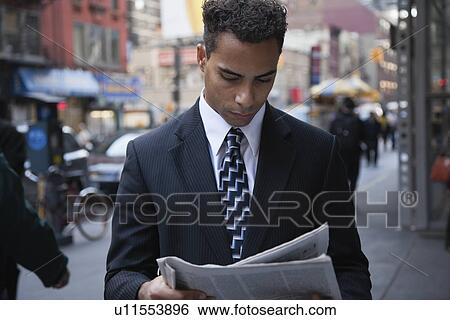 Stock Photograph - USA, New York, New York City, busineeman reading newspaper on street. Fotosearch