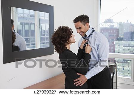 USA, New York, New York City, young woman helping smiling man tying tie in hotel room View Large Photo Image Stock Photo - USA, New York, New York City, young woman helping smiling man tying tie in hotel room. Fotosearch