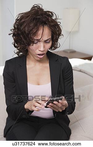 USA, New York State, New York City, business woman using mobile phone on bed View Large Photo Image Picture - USA, New York State, New York City, business woman using mobile phone on bed. Fotosearch