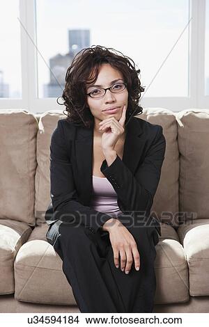 Picture - USA, New York State, New York City, portrait of business woman sitting on sofa. Fotosearch