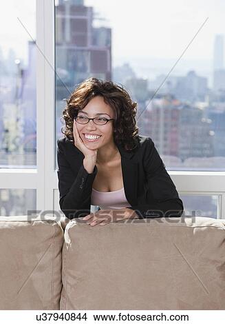 Picture - USA, New York State, New York City, business woman relaxing behind sofa. Fotosearch