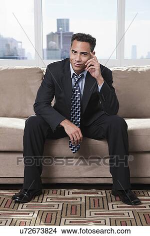 Picture - USA, New York State, New York City, portrait of business man sitting on sofa. Fotosearch