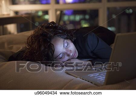 USA, New York State, New York City, young woman asleep by laptop on bed View Large Photo Image Picture - USA, New York State, New York City, young woman asleep by laptop on bed. Fotosearch