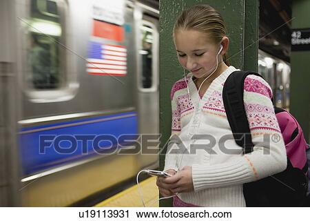 USA, New York State, New York City, Girl (10-11) standing at subway station with earphones and listening music View Large Photo Image Stock Image - USA, New York State, New York City, Girl (10-11) standing at subway station with earphones and listening music . Fotosearch