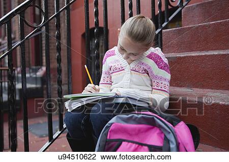 Stock Image - USA, New York State, New York City, Girl (10-11) doing homework while sitting on steps. Fotosearch