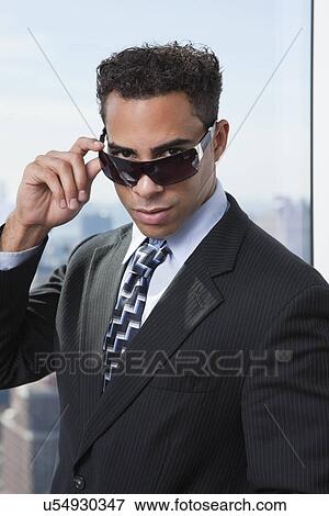 Stock Photo - USA, New York State, New York City, portrait of business man wearing sunglasses. Fotosearch