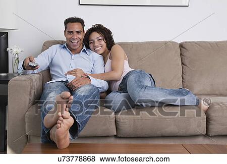 USA, New York State, New York City, young couple watching television on sofa View Large Photo Image Stock Photo - USA, New York State, New York City, young couple watching television on sofa. Fotosearch