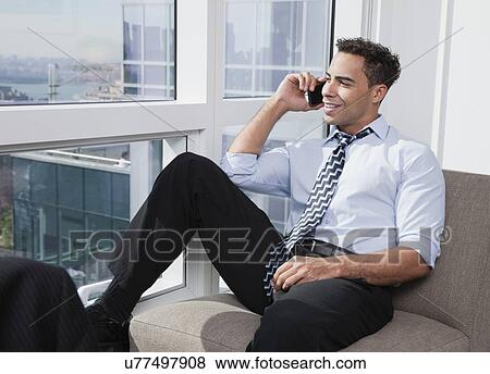 Stock Photo - USA, New York State, New York City, business man using mobile phone by window. Fotosearch