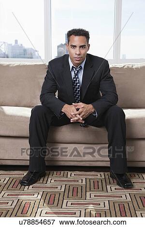 Stock Photo - USA, New York State, New York City, portrait of business man sitting on sofa. Fotosearch
