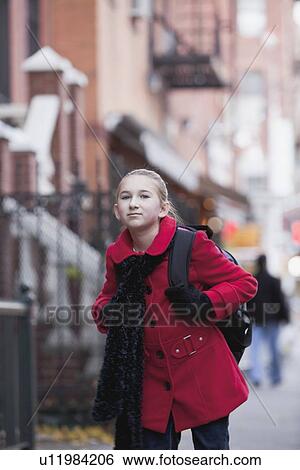 Stock Photograph - USA, New York State, New York City, Girl (10-11) wearing red coat and walking through city. Fotosearch