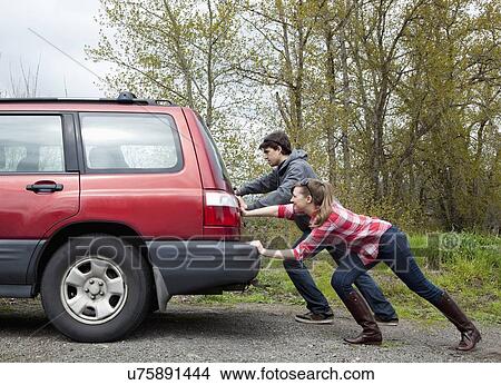 Picture - USA, Oregon, Ashland, young couple pushing car. Fotosearch