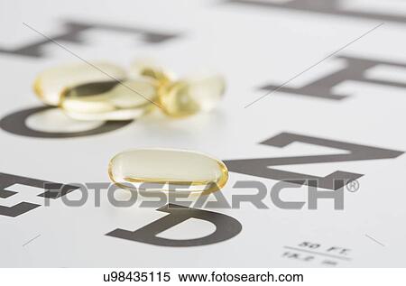 Stock Photography - Vitamins, Gel capsules lying on eye chart. Fotosearch
