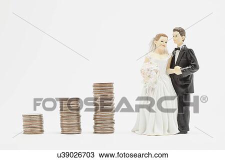 Stock Image - Wedding figurines and stacks of coins, studio shot. Fotosearch