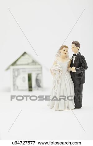 Stock Photo - Wedding figurines in front of house model made of banknotes, studio shot. Fotosearch