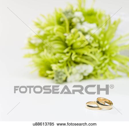 Stock Photography - Wedding rings by bouquet. Fotosearch