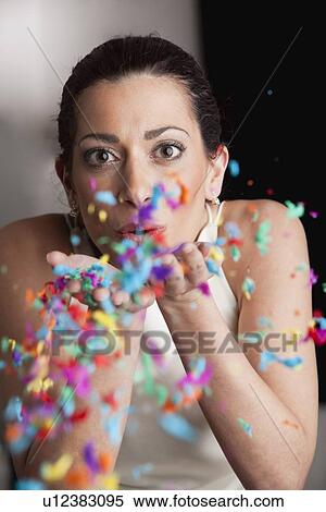 Stock Photography - Woman blowing confetti of her hands. Fotosearch