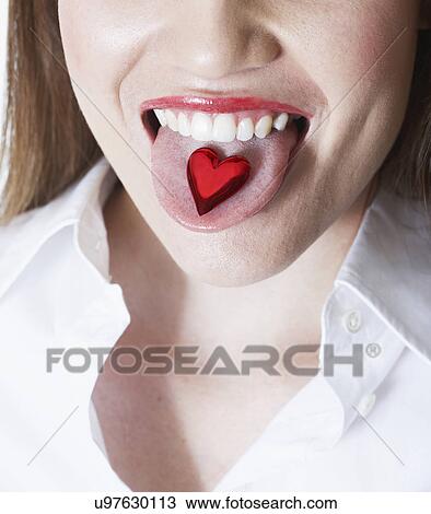 Stock Image - Woman eating heart shape Valentine's candy. Fotosearch
