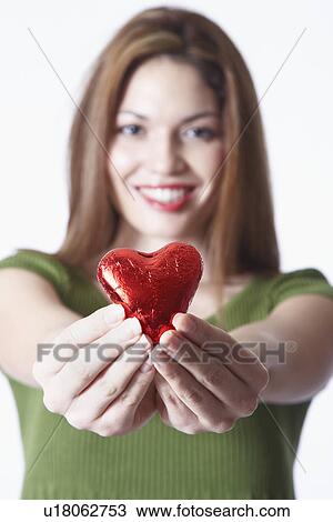 Stock Image - Woman holding heart shape Valentine's gift, portrait. Fotosearch
