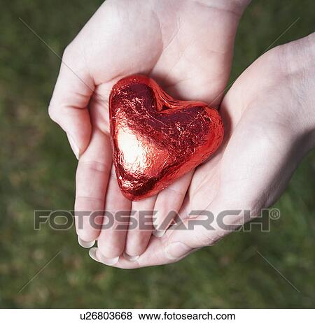 Stock Photo - Woman holding heart shaped candy, Valentine's Day. Fotosearch