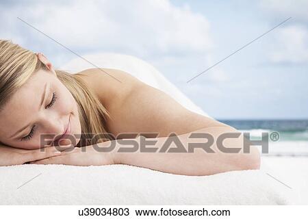 Stock Image - Woman lying on beach. Fotosearch