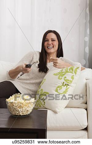Woman sitting on sofa and watching tv View Large Photo Image Stock Image - Woman sitting on sofa and watching tv. Fotosearch
