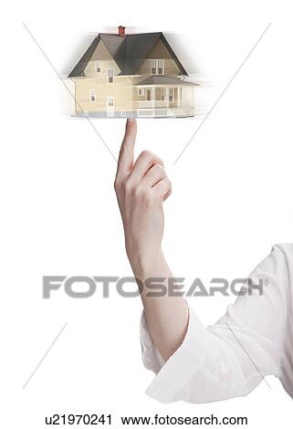 Stock Image - Woman spinning model house on finger. Fotosearch