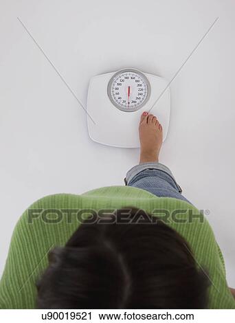 Woman standing on weight scales, view from above View Large Photo Image Stock Image - Woman standing on weight scales, view from above. Fotosearch