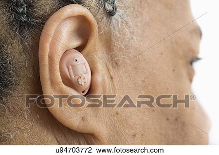 Stock Image - Woman with hearing aid, close up. Fotosearch